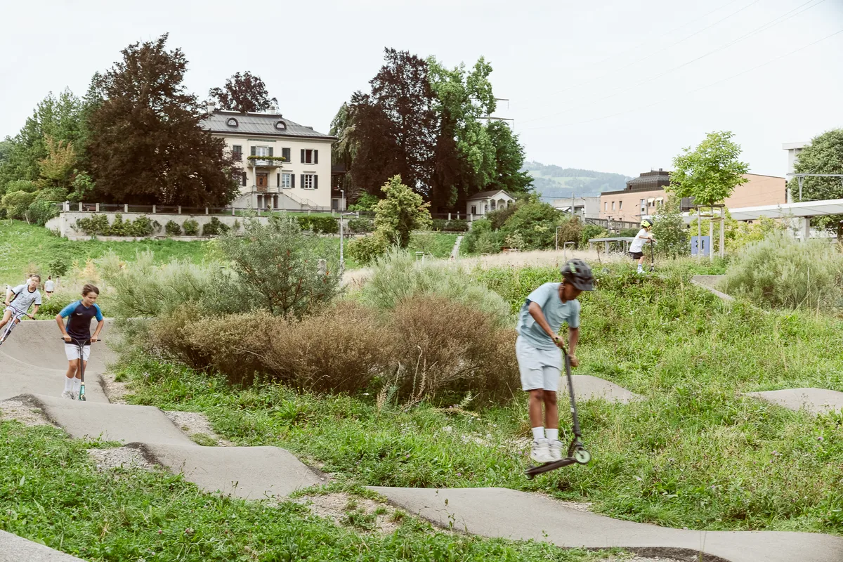 Der Grünfelspark in Jona liegt unweit des Bahnhofs. Kinder mit Scootern fahren auf einem Pumptrack.